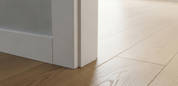 Close-up of light wood flooring meeting a white wall corner, showcasing sleek design and smooth textures. The tone is modern and minimalist.