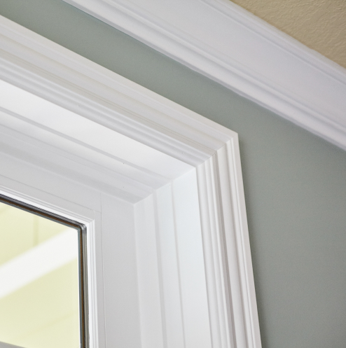 Close-up of an interior corner shows elegant white crown molding against pale green walls, creating a crisp and clean architectural detail.