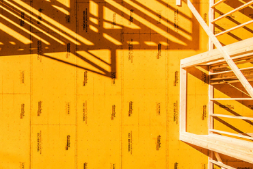 Aerial view of a house under construction with yellow ZIP System sheathing installed on exterior wall framing.