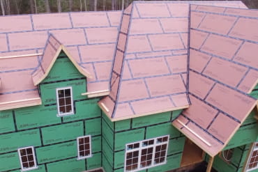 Aerial view of a house under construction fully wrapped in ZIP System wall and roof sheathing with taped seams.